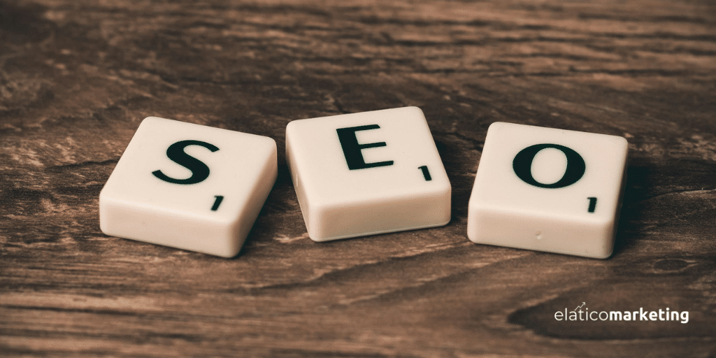 Piezas blancas de Scrabble formando la palabra SEO, situadas sobre una superficie de madera oscura.